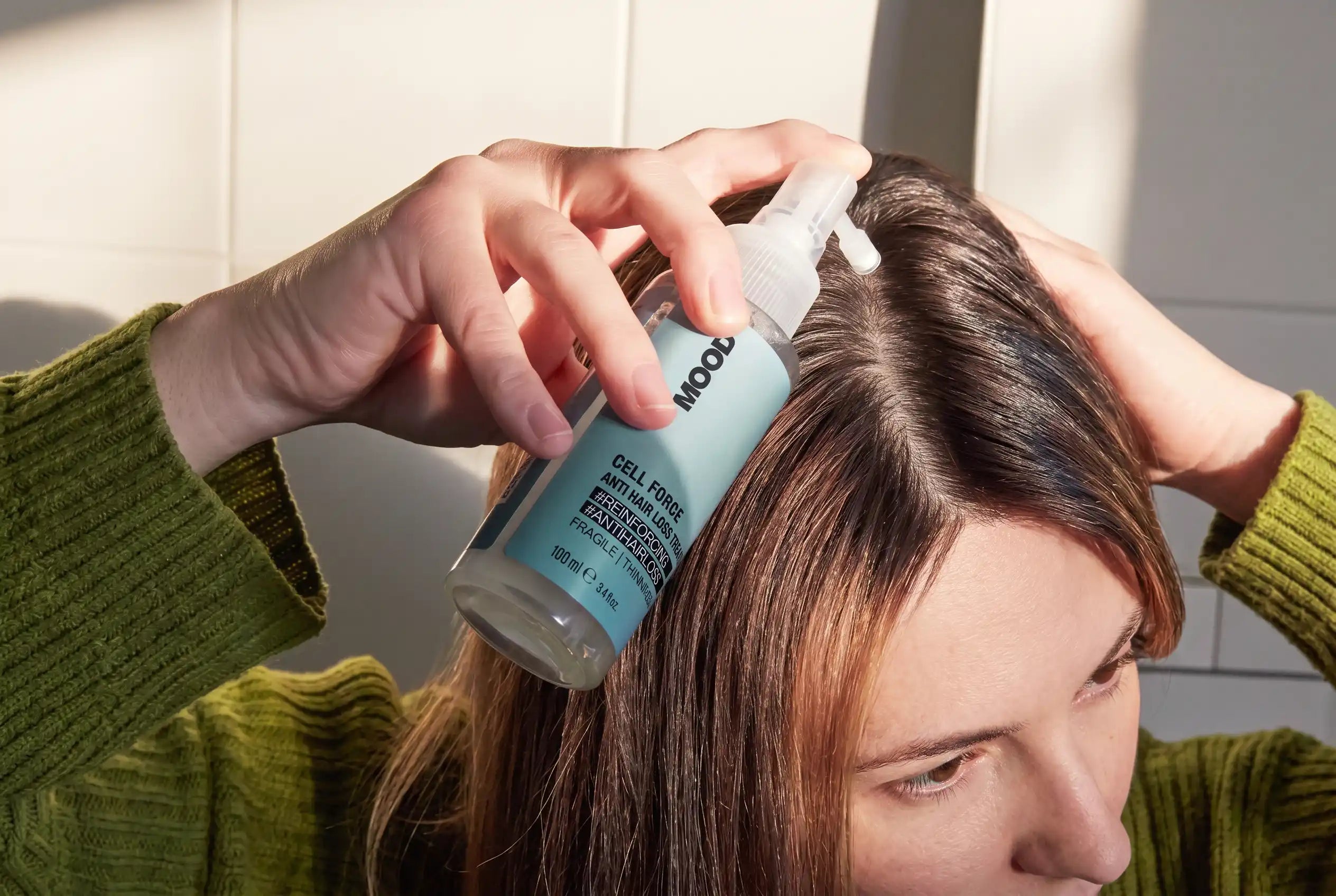Hoofdafbeelding van de Cell Force haarverzorgingslijn met een model dat de anti-haaruitval behandeling rechtstreeks op de hoofdhuid aanbrengt.
