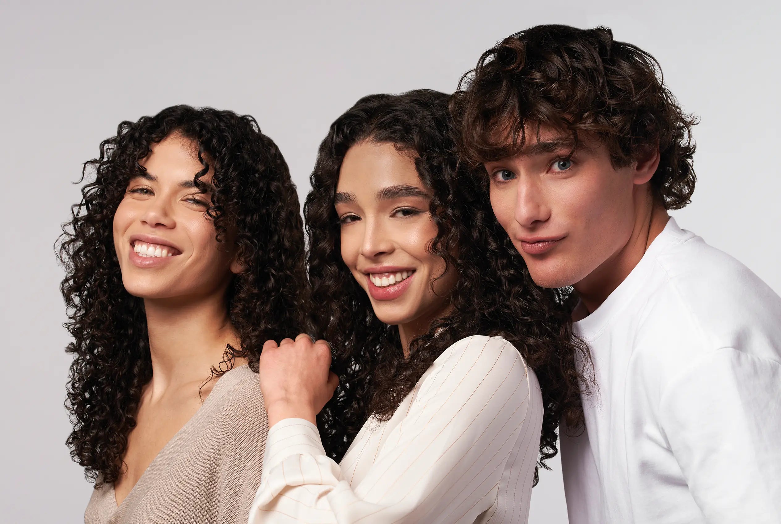Hoofdafbeelding van de Dream Curls haarverzorgingslijn met drie modellen met gezonde, glanzende en goed gedefinieerde krullen.